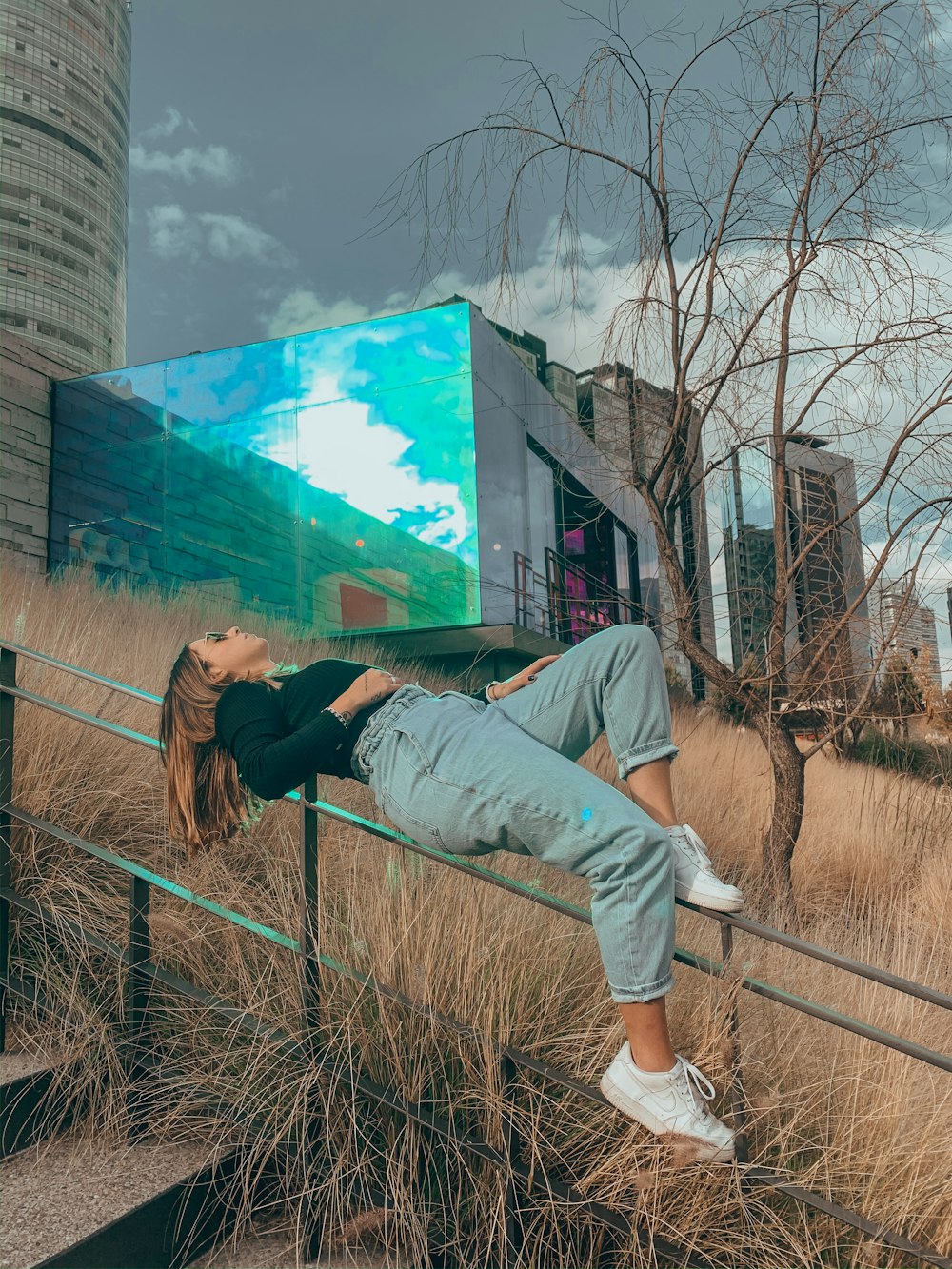 woman in gray t-shirt and gray pants standing on brown wooden fence during daytime