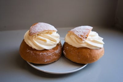 two brown bread on white ceramic plate buns teams background