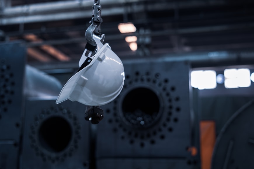 A white hard hat hanging from the ceiling in a factory