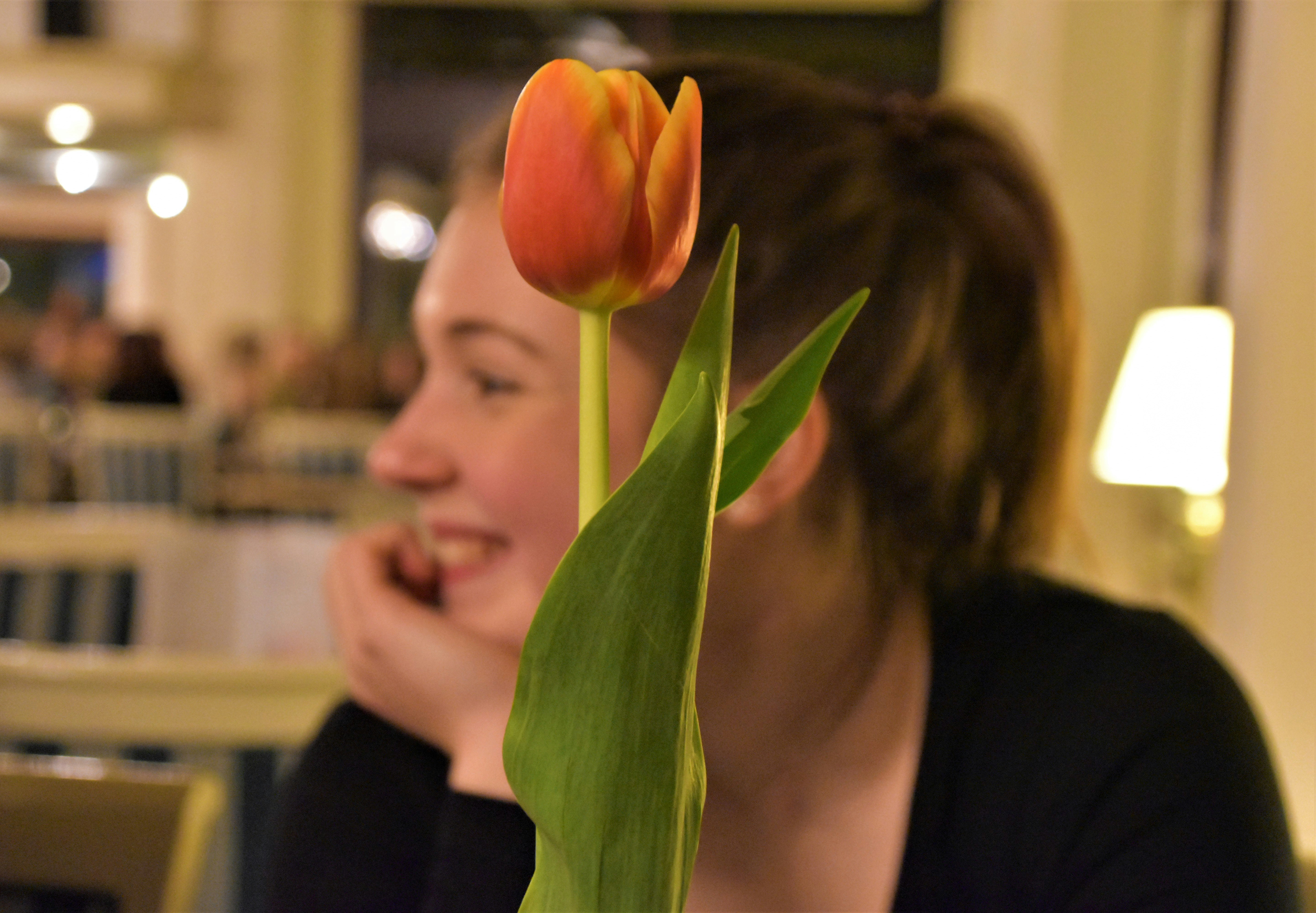 woman in black shirt holding orange tulip