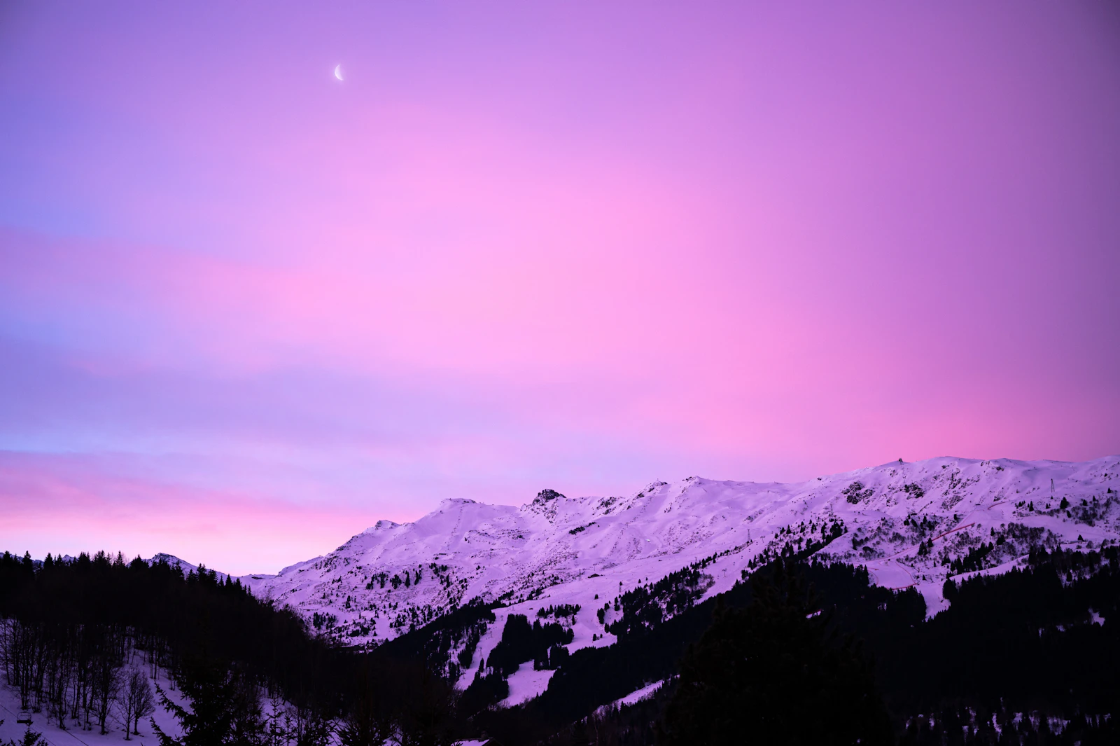 Méribel at dusk, the village lights under a pink sky
