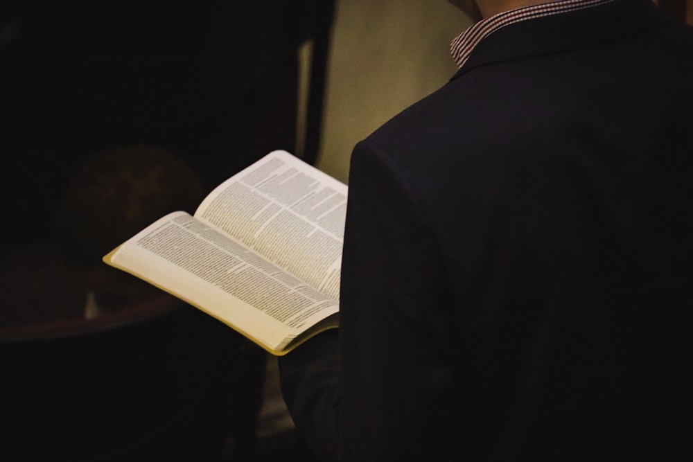 person reading book on black textile