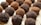 Chocolate truffles are arranged in a close-up view on a wooden surface. Some truffles are coated in cocoa powder while others have a darker, crumbly chocolate coating.