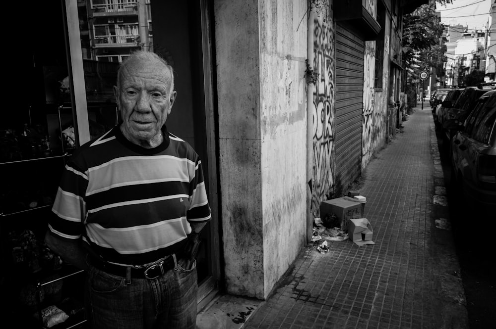 man in striped shirt and denim jeans standing beside wall