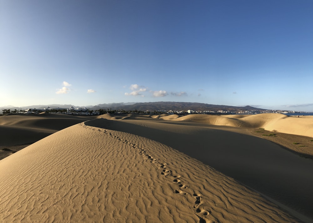 areia marrom sob o céu azul durante o dia