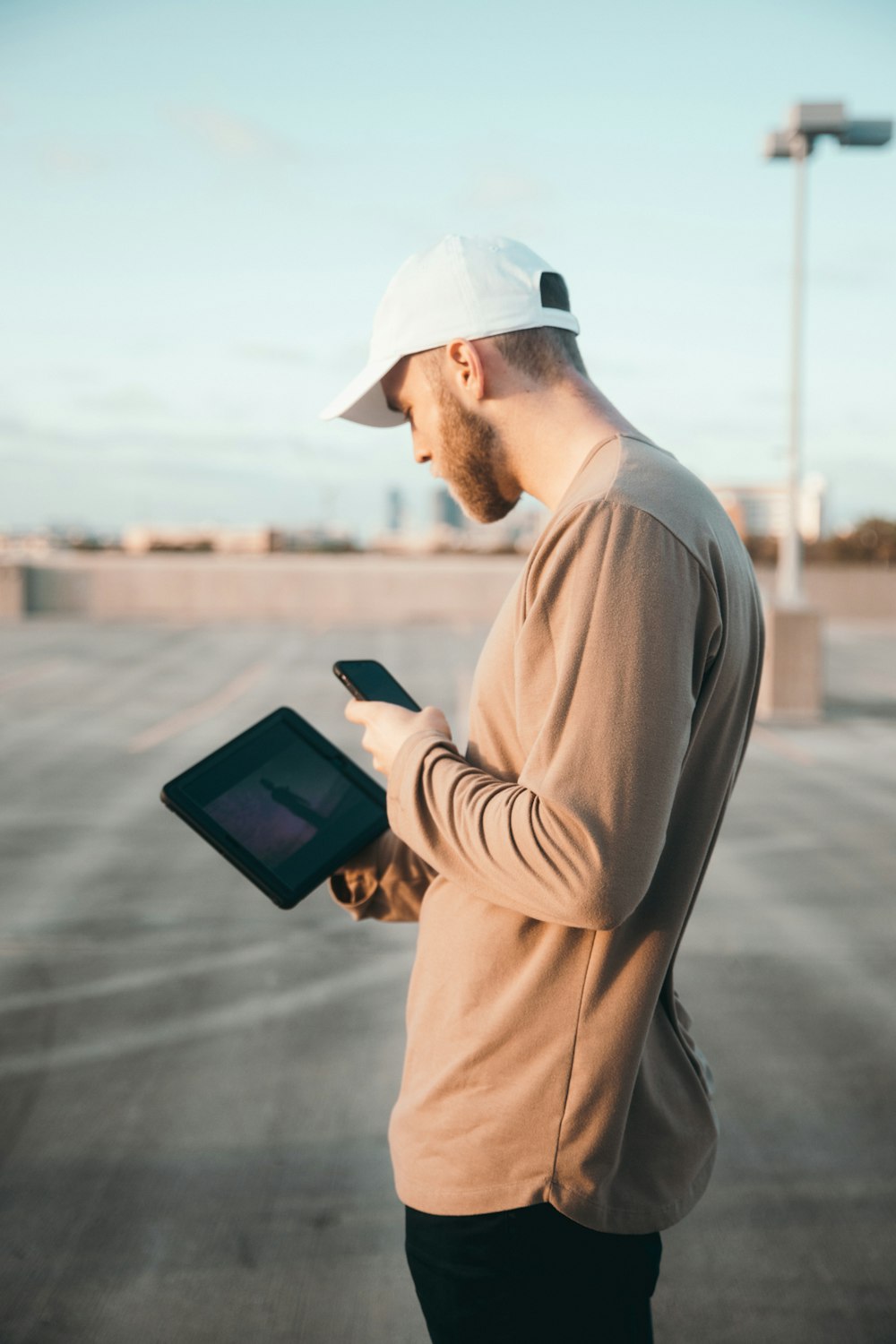 man in brown sweater holding black tablet computer