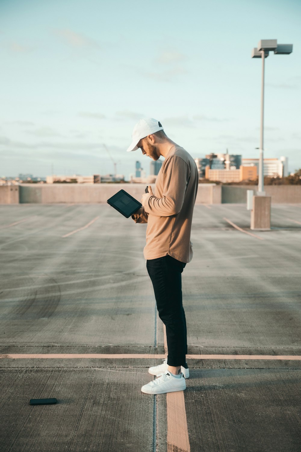 man in brown hoodie and black pants holding black tablet computer