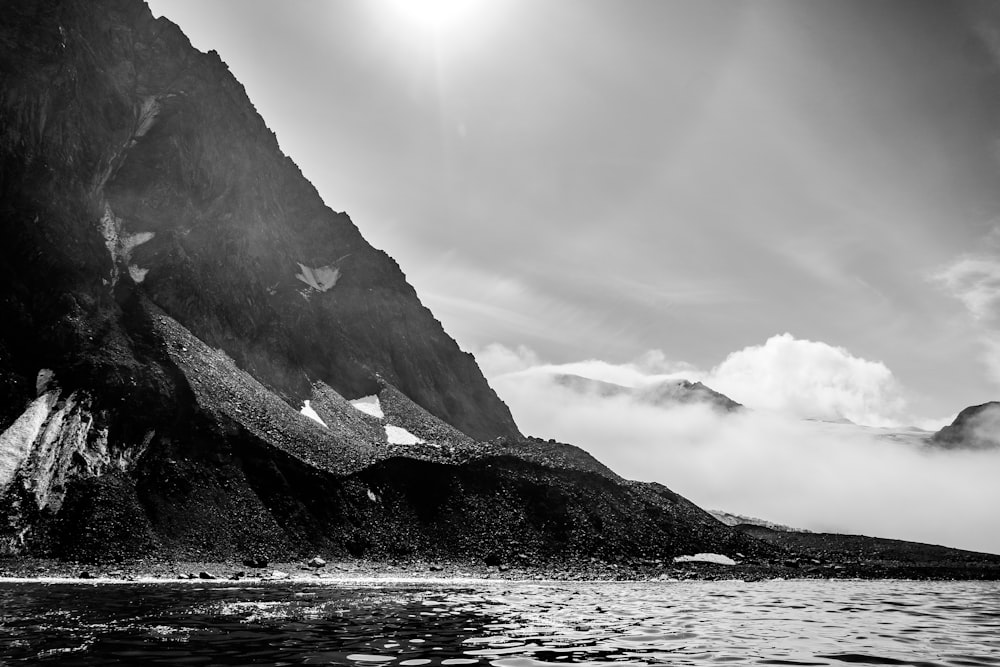 grayscale photo of mountain near body of water