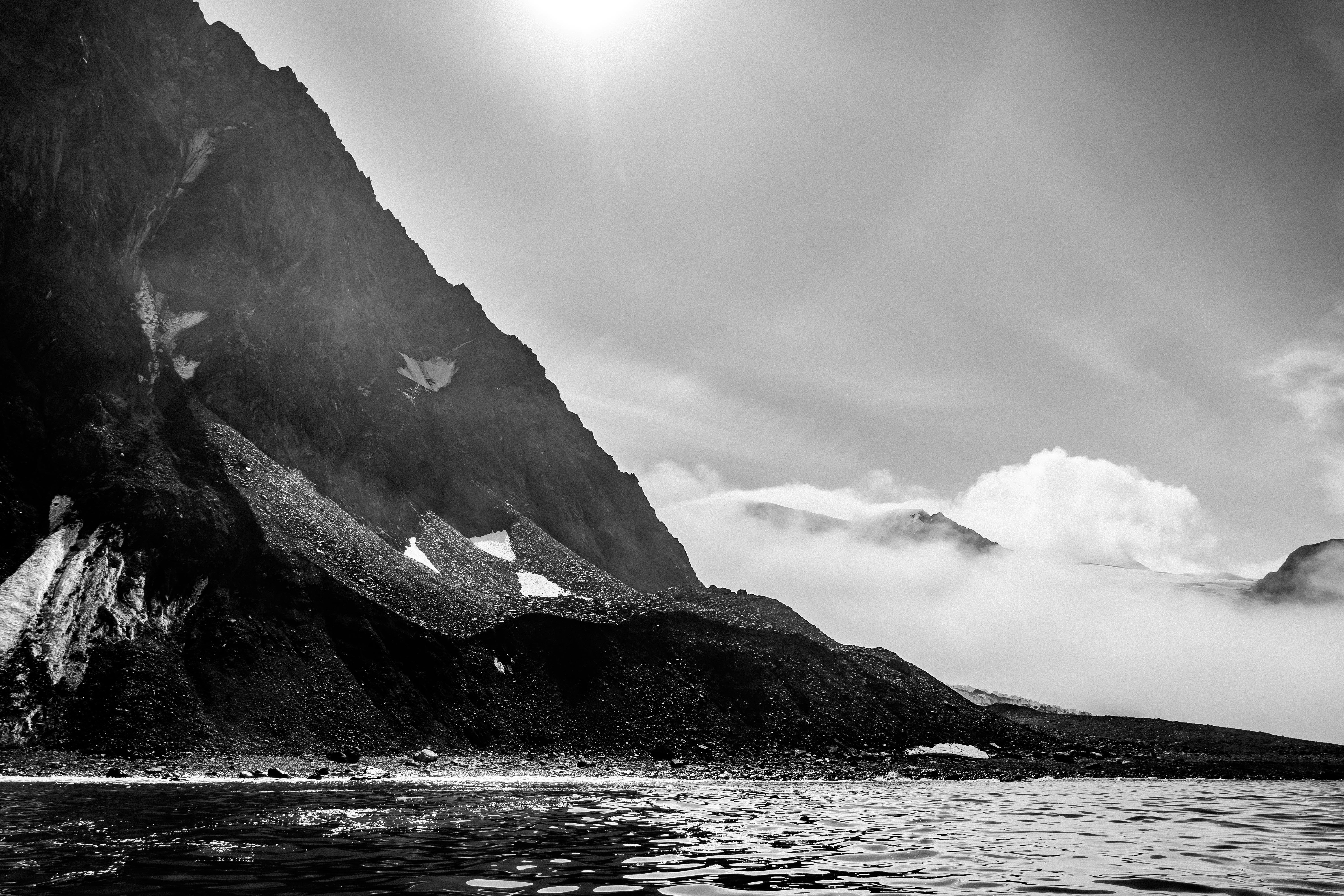 grayscale photo of mountain near body of water