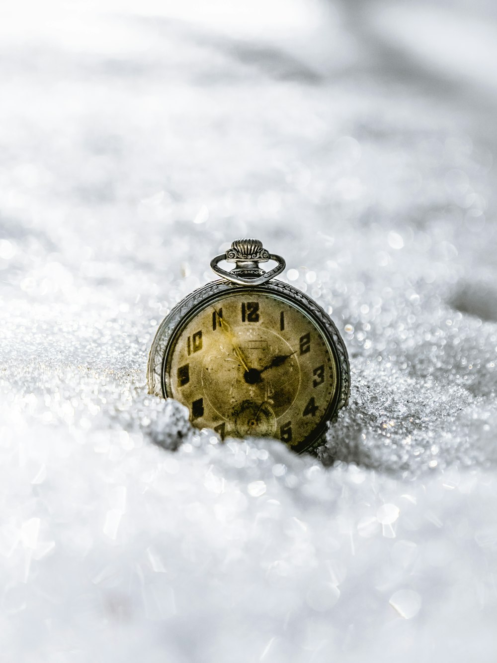 Reloj de bolsillo redondo dorado y negro sobre nieve