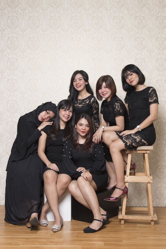 3 women sitting on brown wooden chair