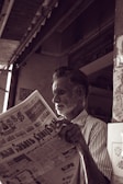 man in white and black striped dress shirt reading newspaper