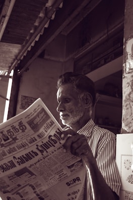 man in white and black striped dress shirt reading newspaper