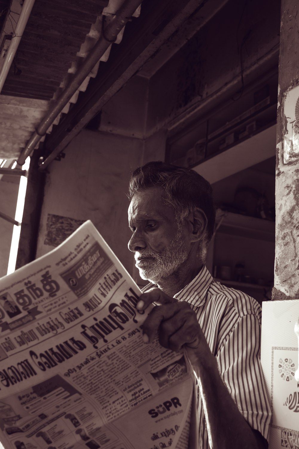 man in white and black striped dress shirt reading newspaper