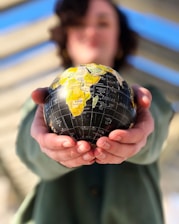 person holding yellow and black desk globe