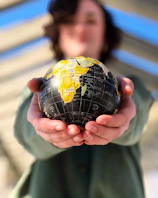 person holding yellow and black desk globe