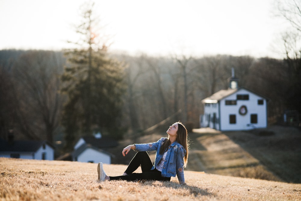 woman in blue denim jacket sitting on brown dirt during daytime