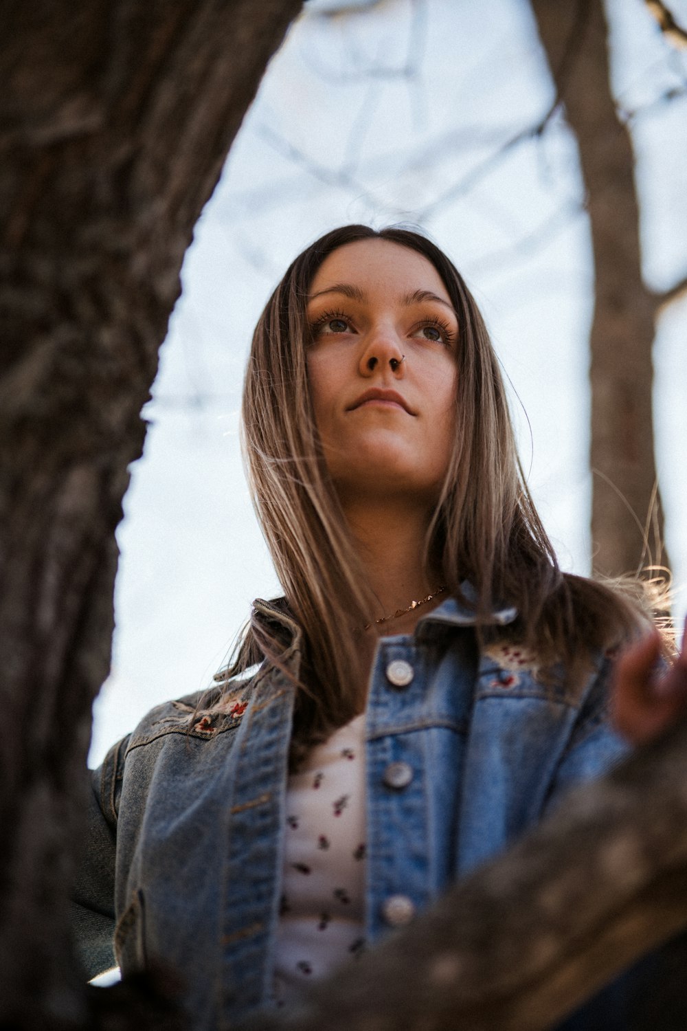 woman in blue denim jacket standing near brown tree during daytime