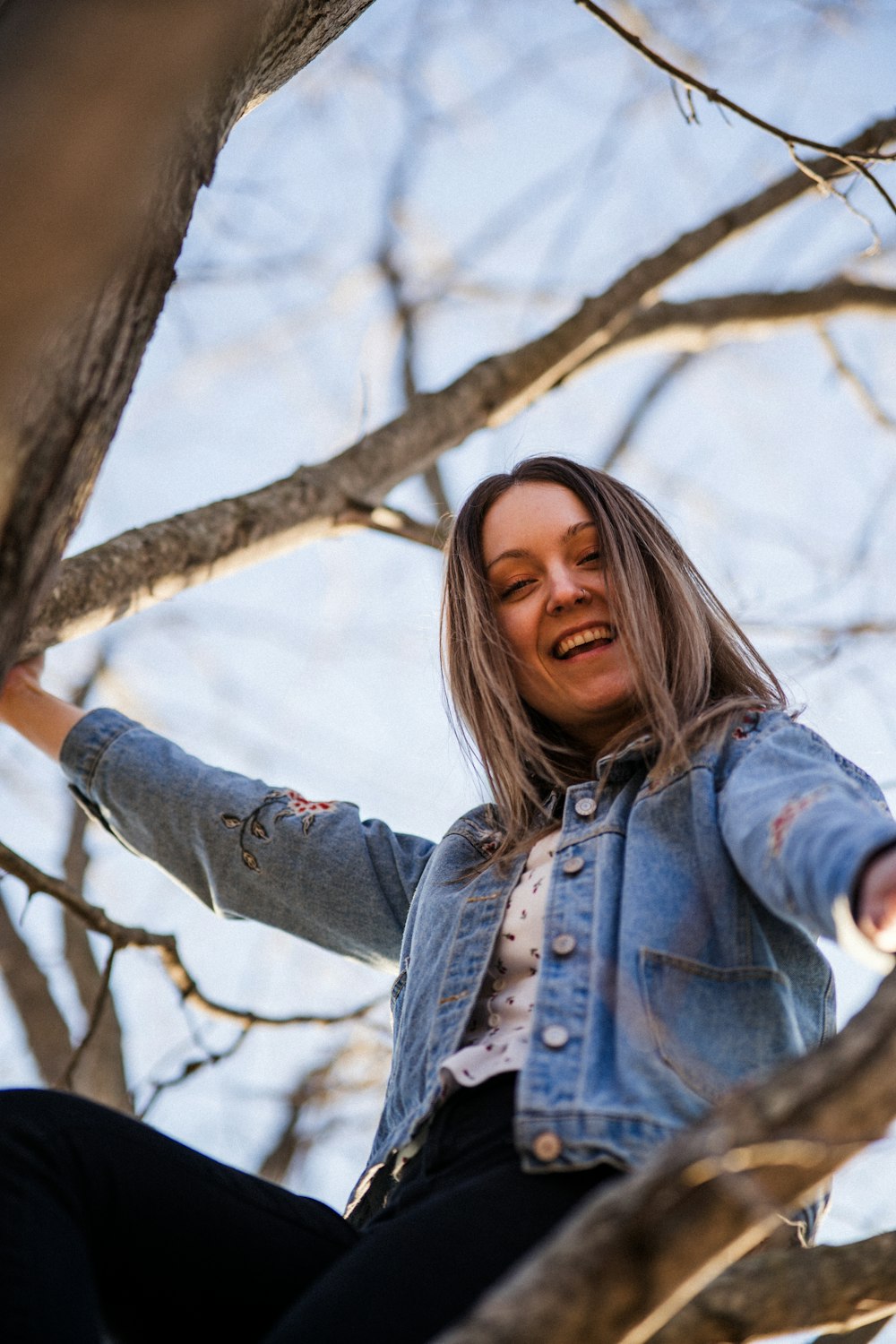 woman in blue denim jacket standing near tree during daytime