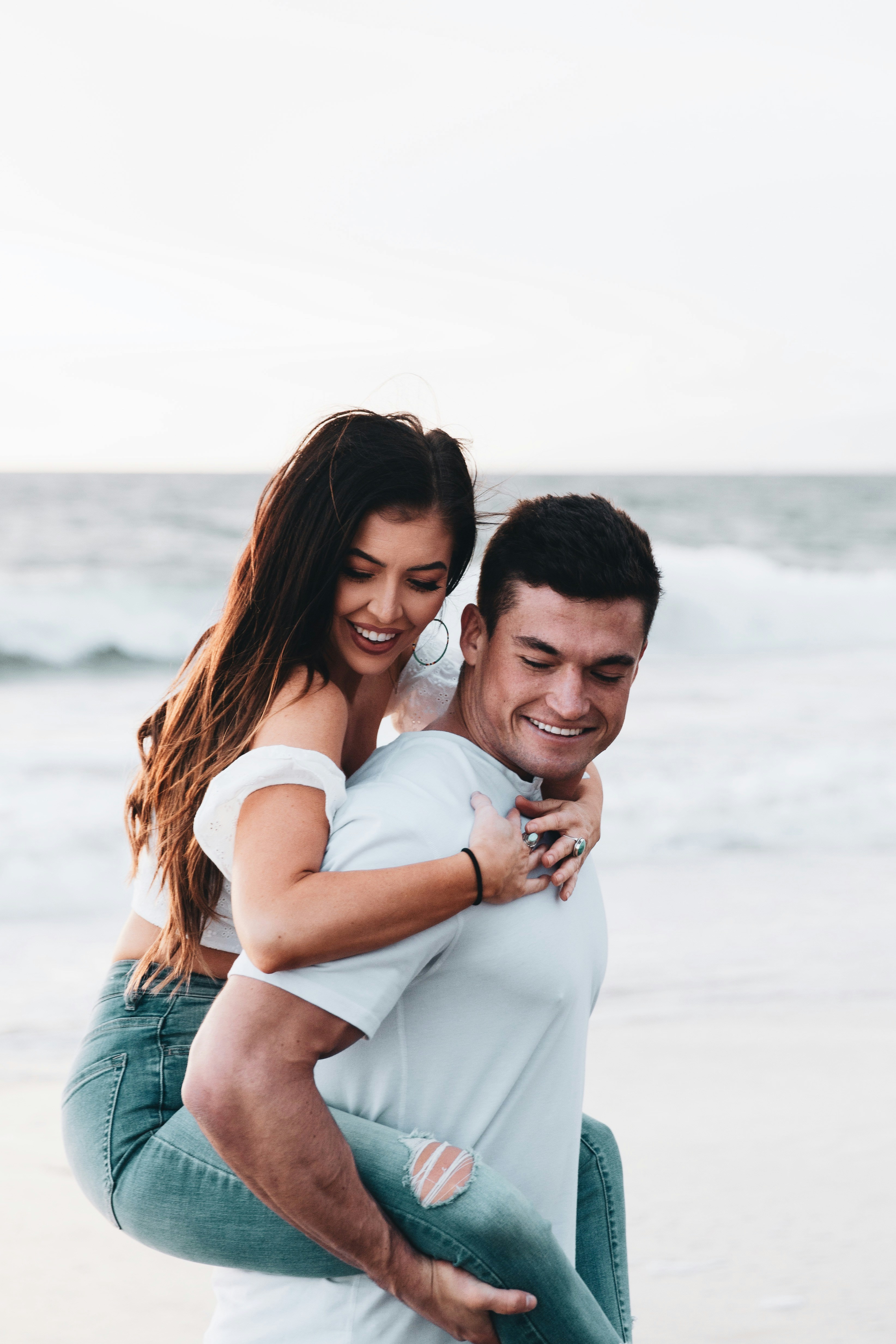 man in white shirt hugging woman in white shirt on beach during daytime