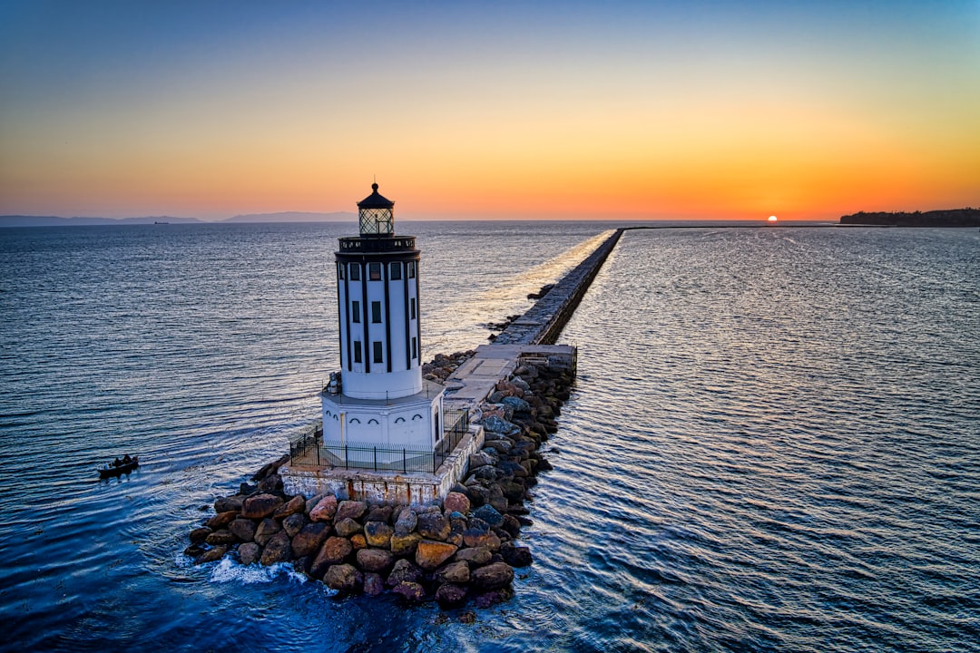 white lighthouse near body of water during sunset