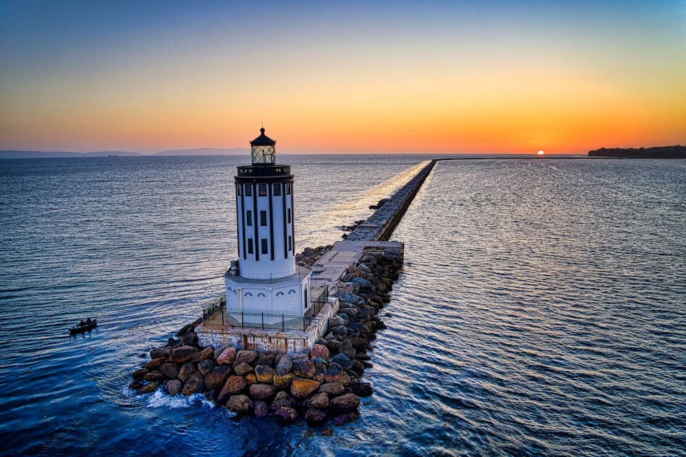 white lighthouse near body of water during sunset