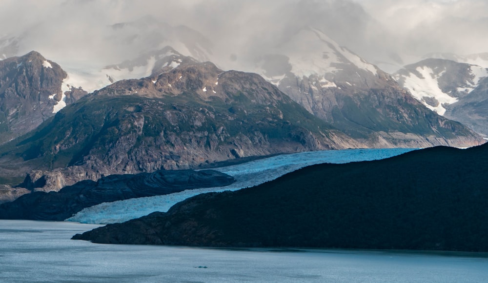 snow covered mountain near body of water during daytime