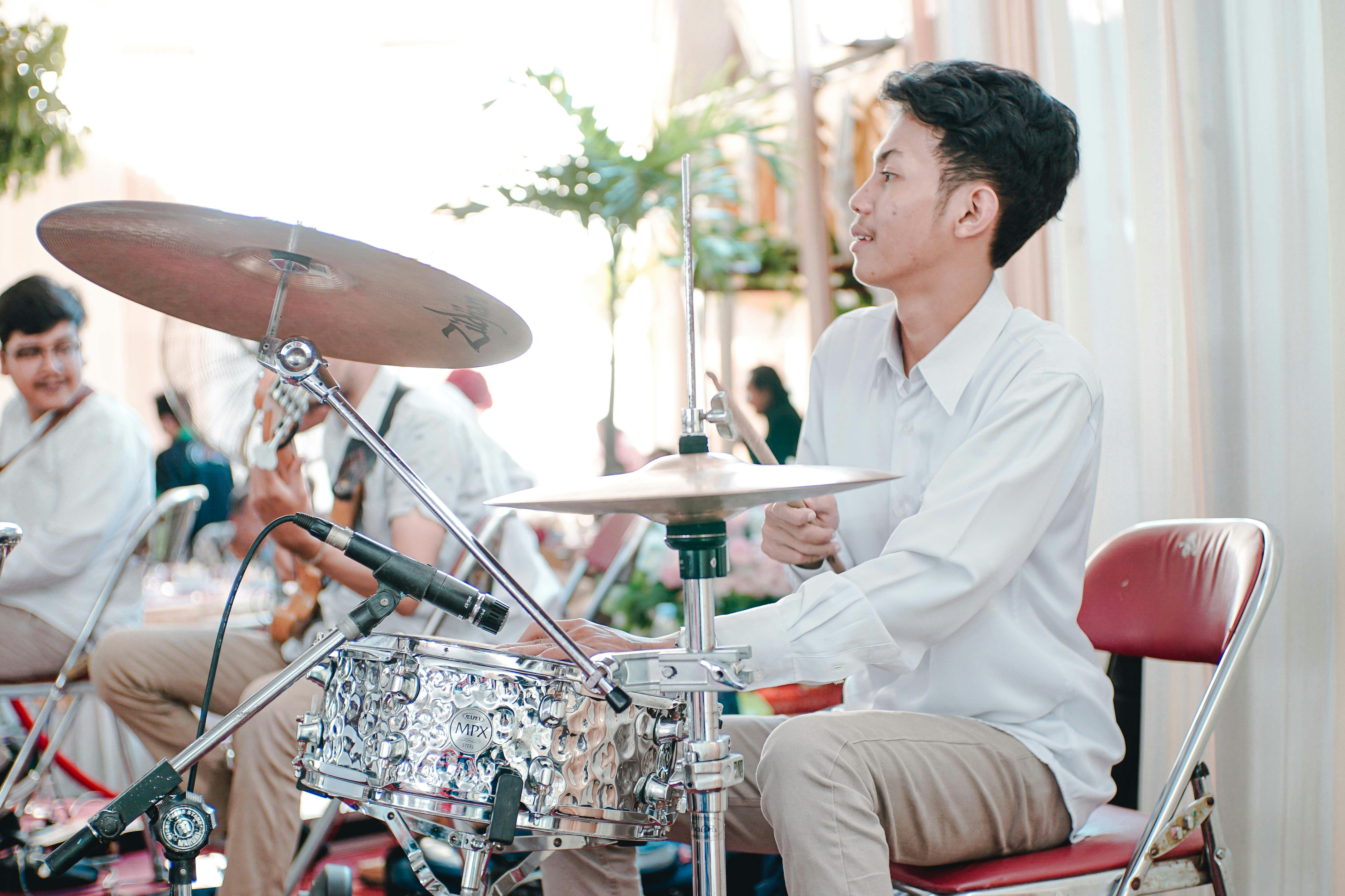 man in white dress shirt playing electric drum set