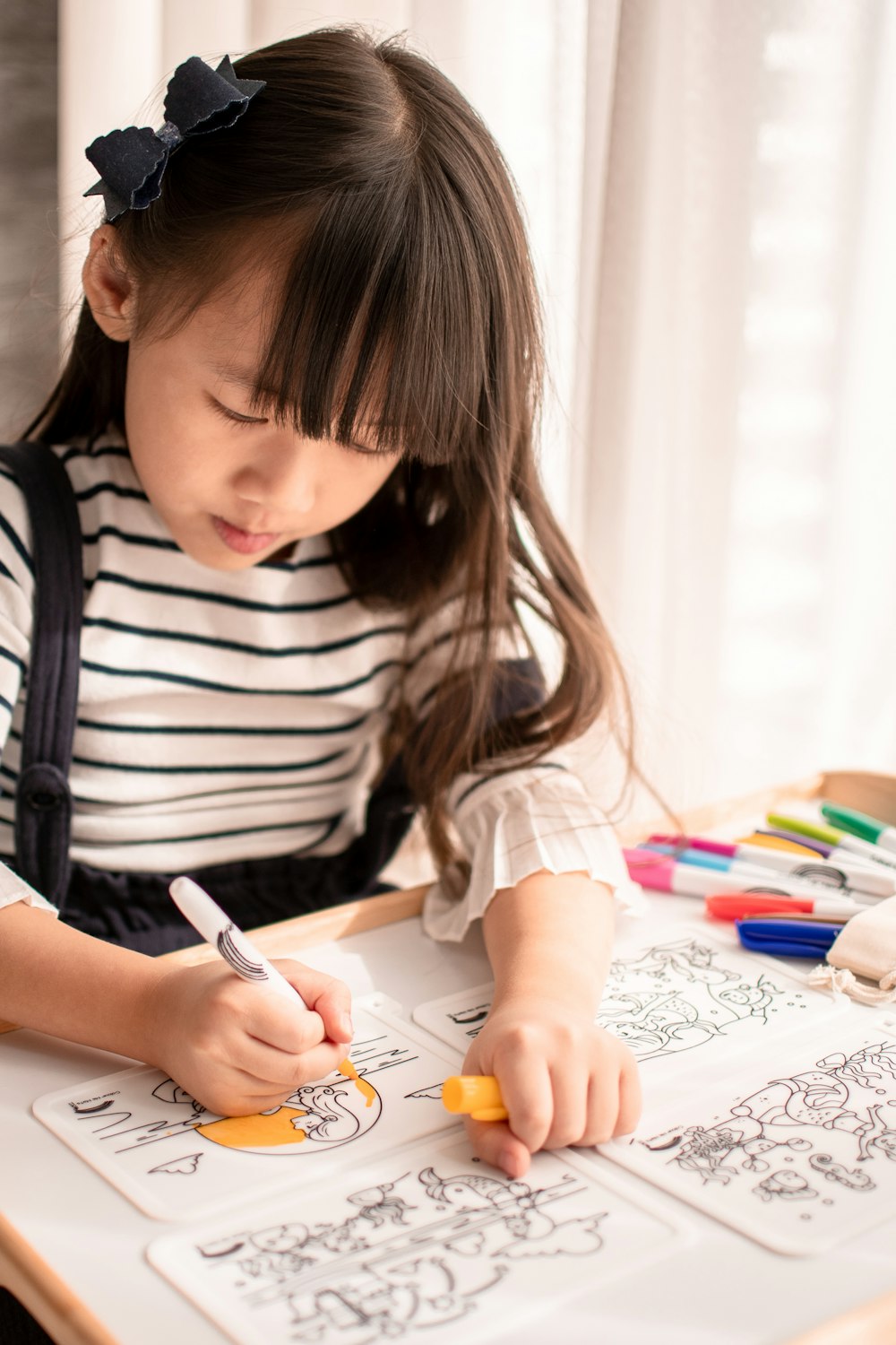 girl in white and black stripe long sleeve shirt writing on white paper