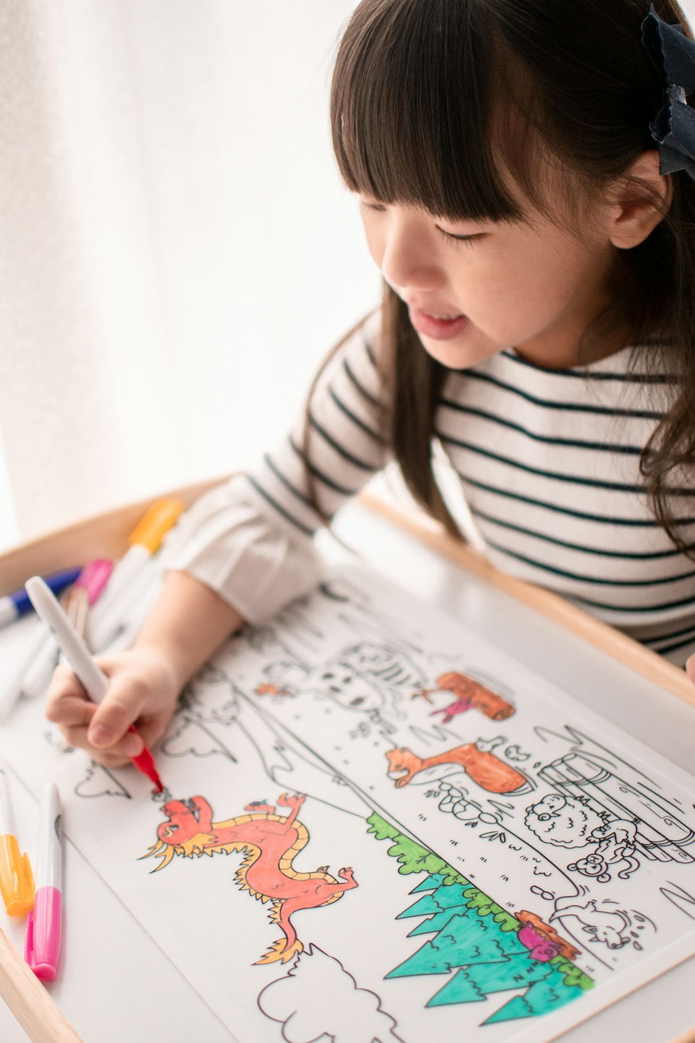 girl in white and black striped long sleeve shirt drawing on white paper