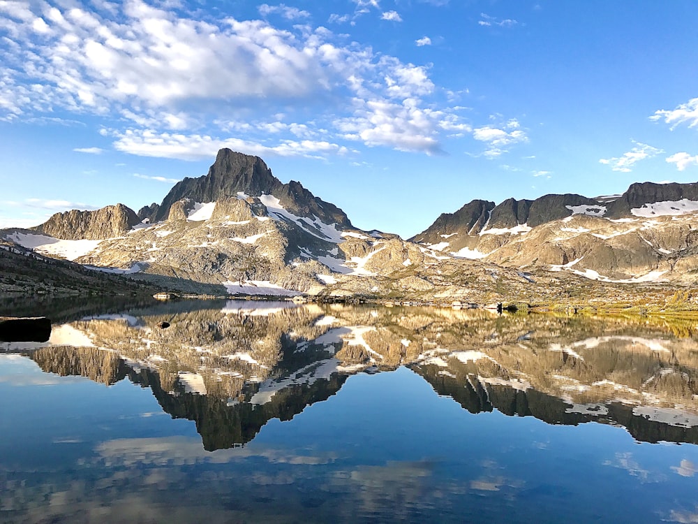 brown and white mountains near body of water under blue sky during daytime