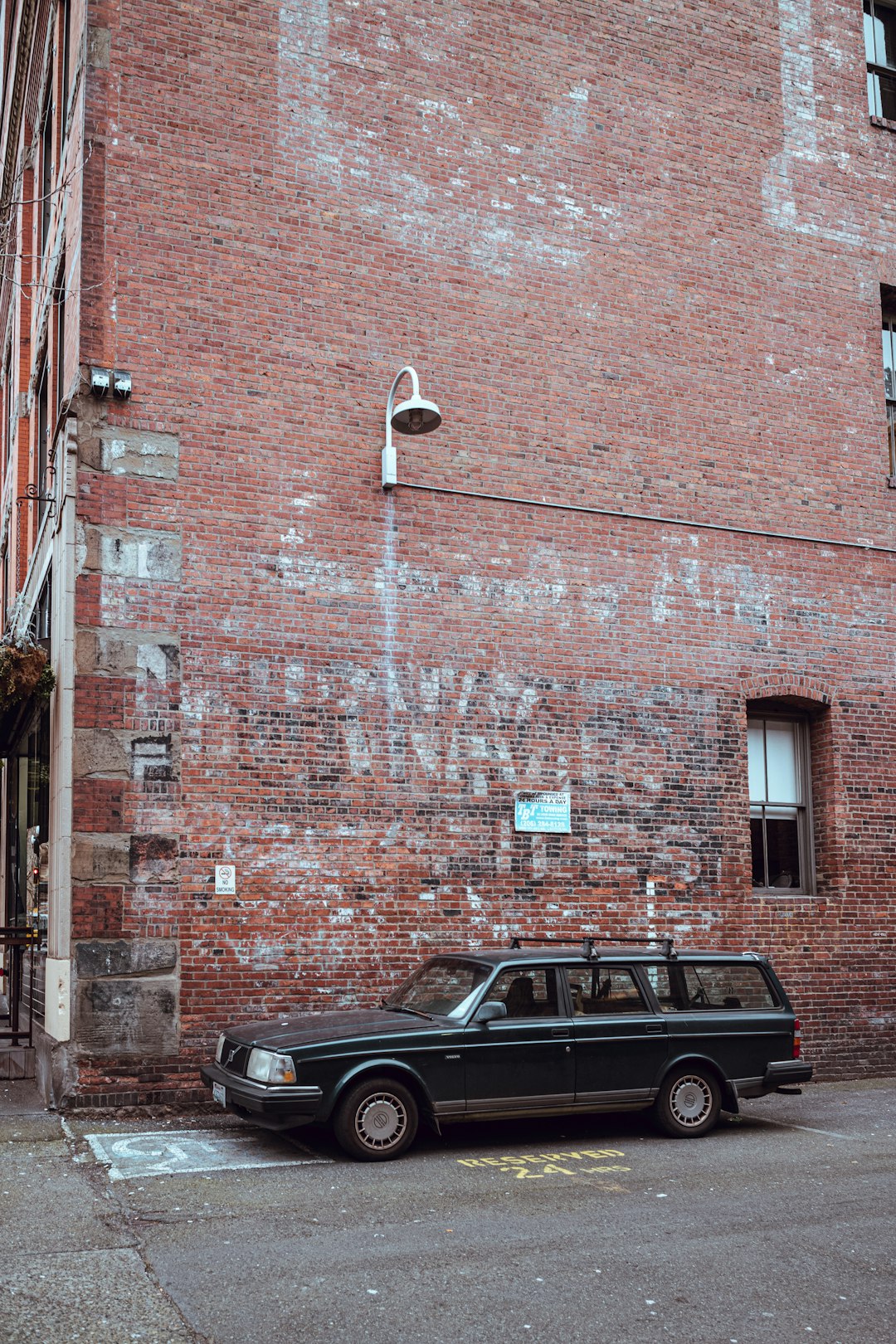 black car parked beside brown brick building