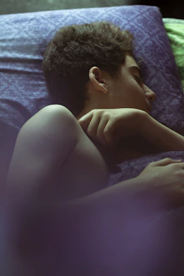 topless man lying on bed