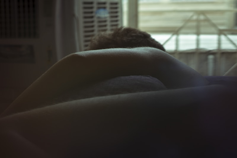 person lying on bed near window