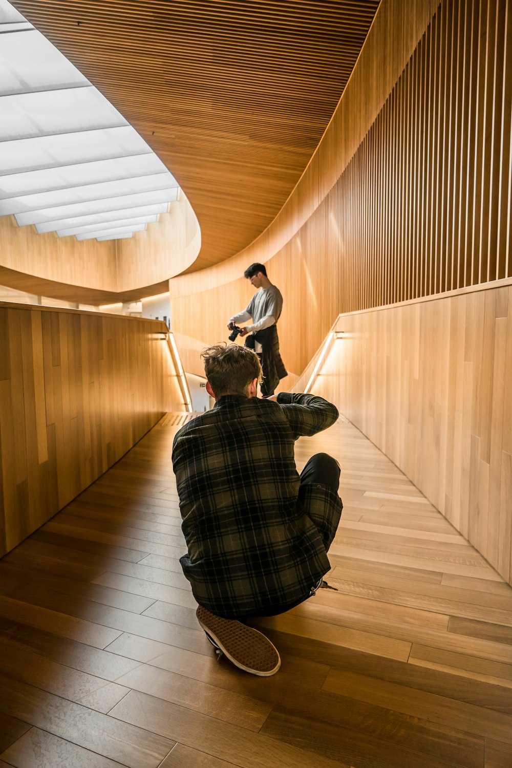 man in black and white plaid dress shirt sitting on brown wooden floor