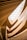 An architectural interior featuring multiple layers of wooden slats and curved structures, which create a flowing, organic pattern. Natural light filters through a large skylight above, highlighting the warm hues of the wood and the gentle curves of the design.
