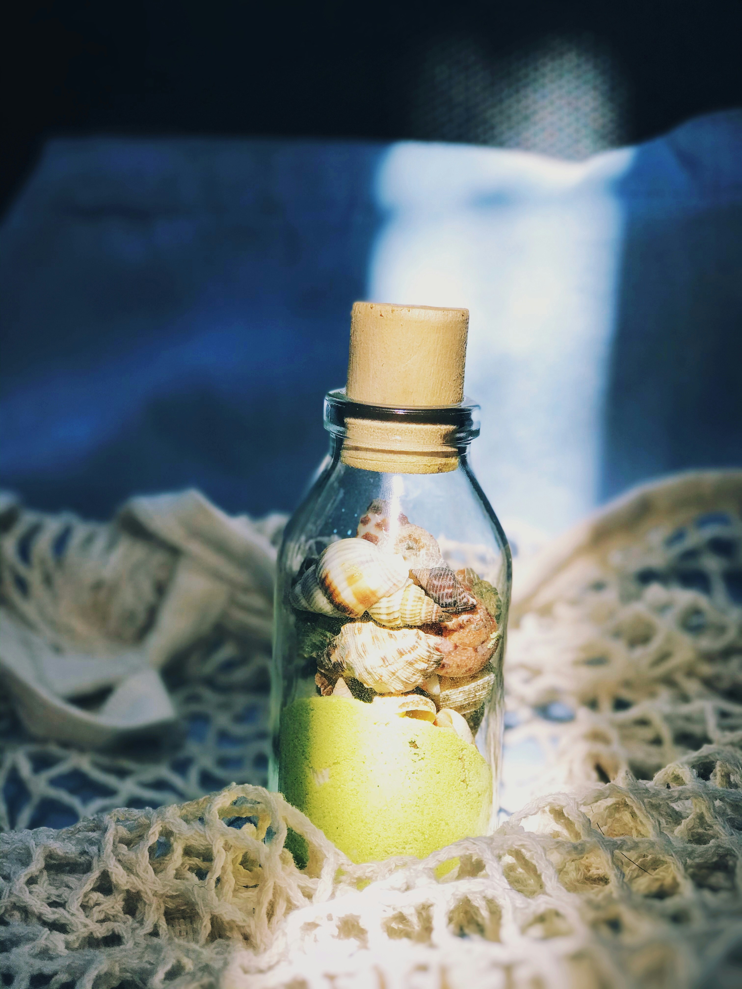 a glass bottle filled with sand and shells
