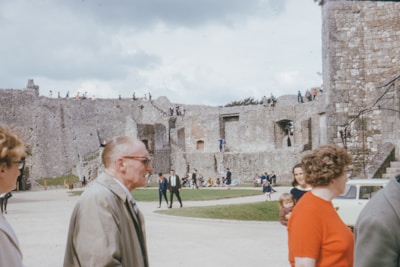 Ancient castle ruins bathed in warm sunlight with tourists exploring.