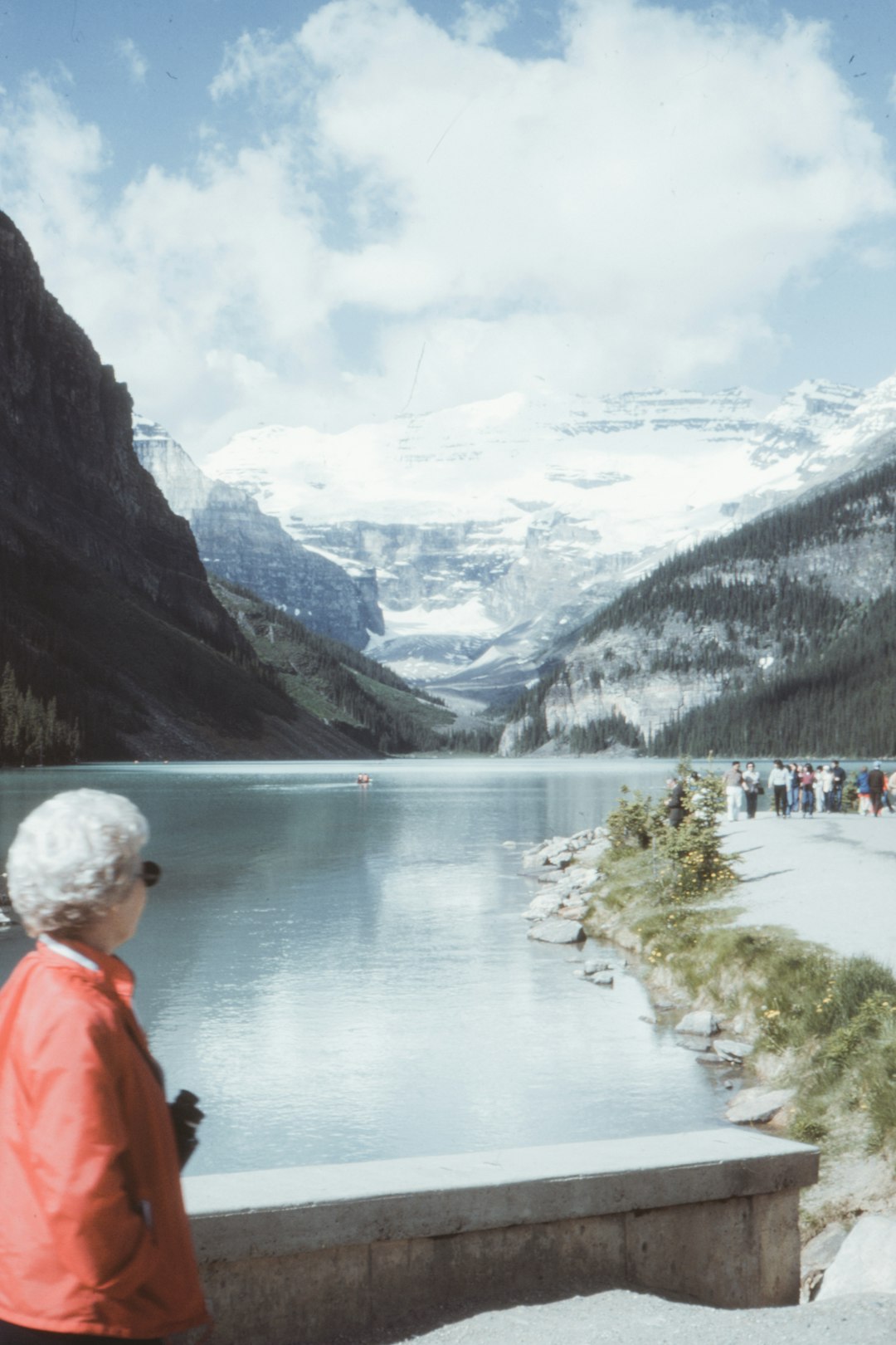 man in orange jacket standing near lake during daytime