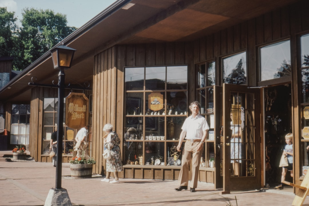 man in white t-shirt and brown pants standing in front of store during daytime
