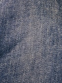 Close-up view of a denim fabric surface with interwoven blue and white threads creating a textured pattern.