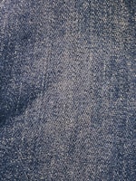 Close-up view of a denim fabric surface with interwoven blue and white threads creating a textured pattern.