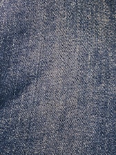 Close-up view of a denim fabric surface with interwoven blue and white threads creating a textured pattern.