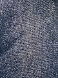 Close-up view of a denim fabric surface with interwoven blue and white threads creating a textured pattern.
