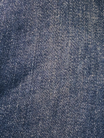 Close-up view of a denim fabric surface with interwoven blue and white threads creating a textured pattern.