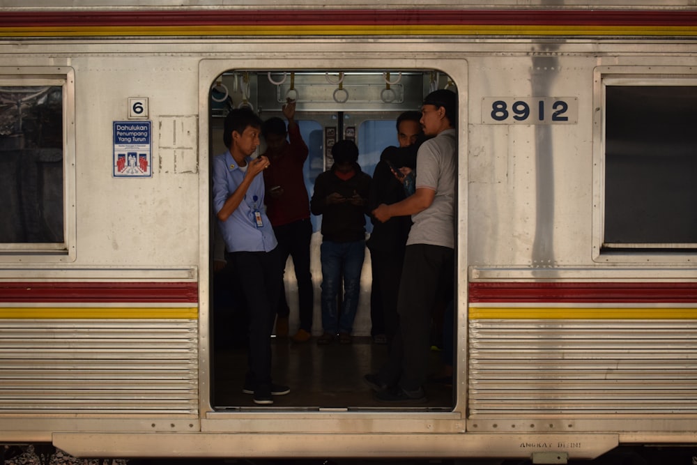 3 hombres y 2 mujeres de pie frente a un tren blanco