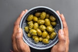 Artisan hands pouring fresh olive oil into a tasting dish.