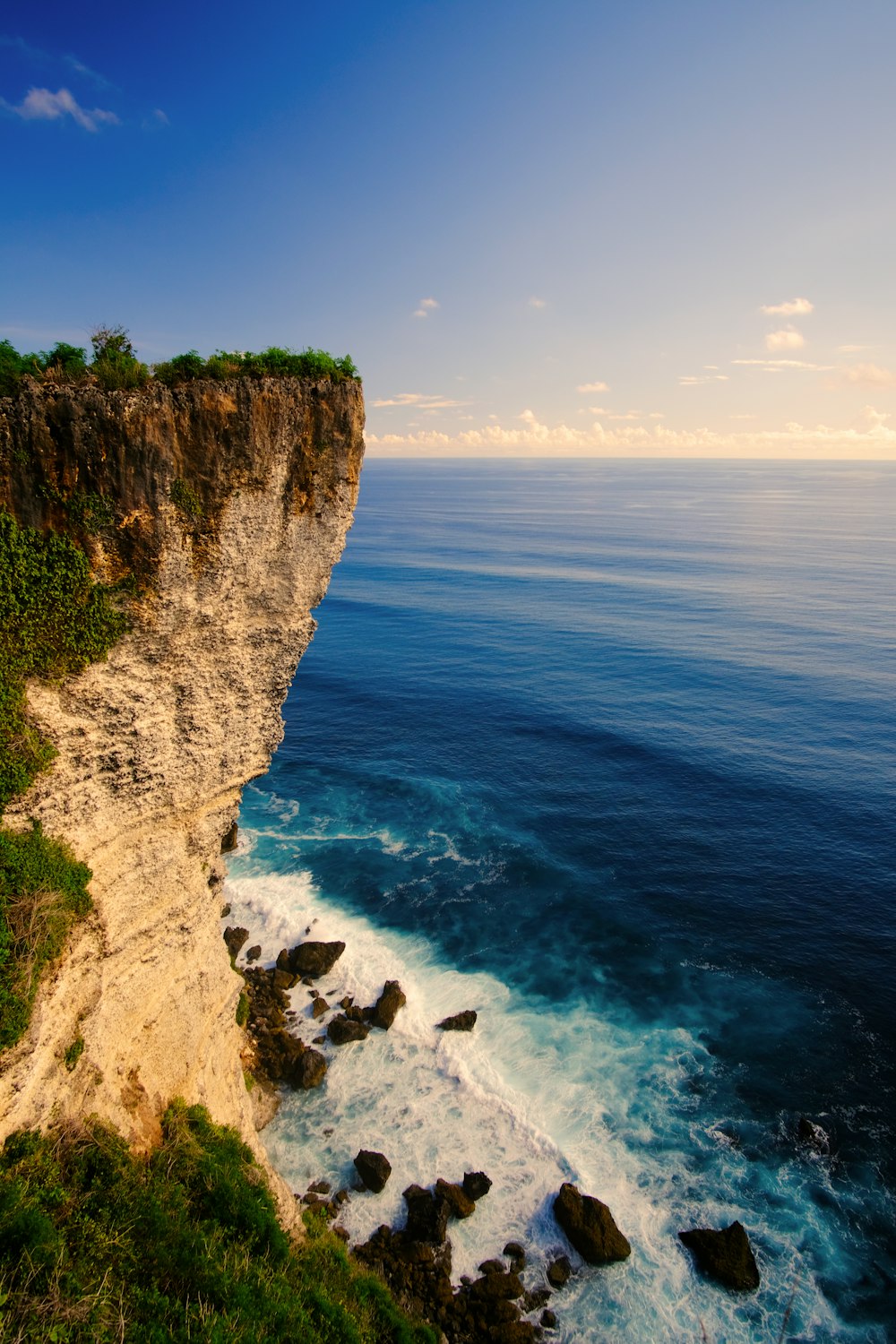 brown rocky mountain beside blue sea under blue sky during daytime