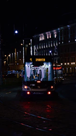 Night scene showing a vėjas keltas tow truck navigating city streets with flashing lights.