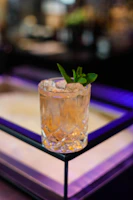Close-up of a crystal glass filled with Edinburgh Gin, set against a dark navy background with soft golden highlights.